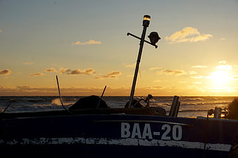 Fishing boat silhouette at sunset with registration BAA-20