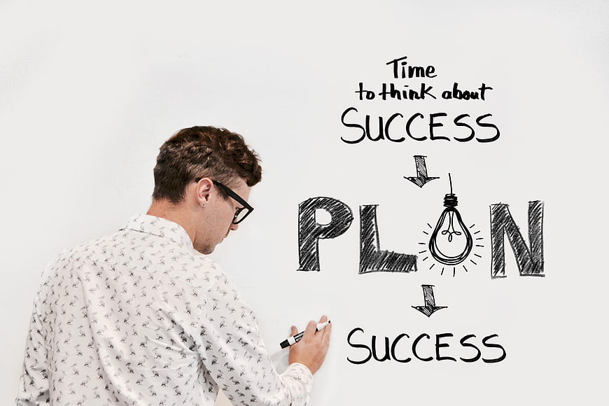 Man writing business strategy plan on whiteboard