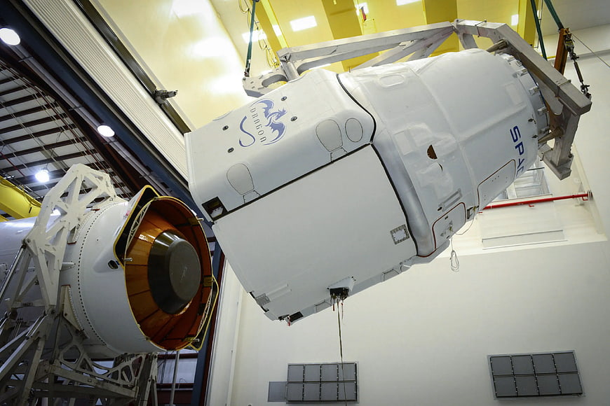 SpaceX Dragon spacecraft suspended in assembly facility