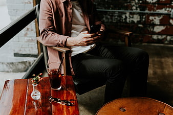 Man sitting in cafe using smartphone with iced coffee