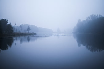 Misty river landscape with foggy trees and reflections at dawn