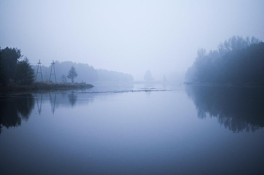 Misty river landscape with foggy trees and reflections at dawn
