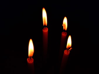 Four lit red candles glowing in the dark