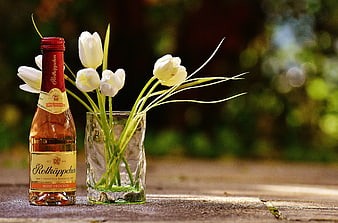 Rothkappchen Rosé Wine Bottle with White Tulips on Wooden Table