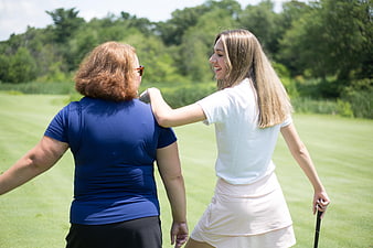 Two women golfers laughing together on a sunny green course