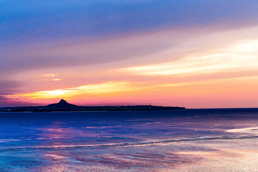 Vibrant Sunset Over Ocean with Distant Island Silhouette