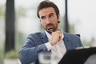 Thoughtful businessman in blue suit thinking at office desk
