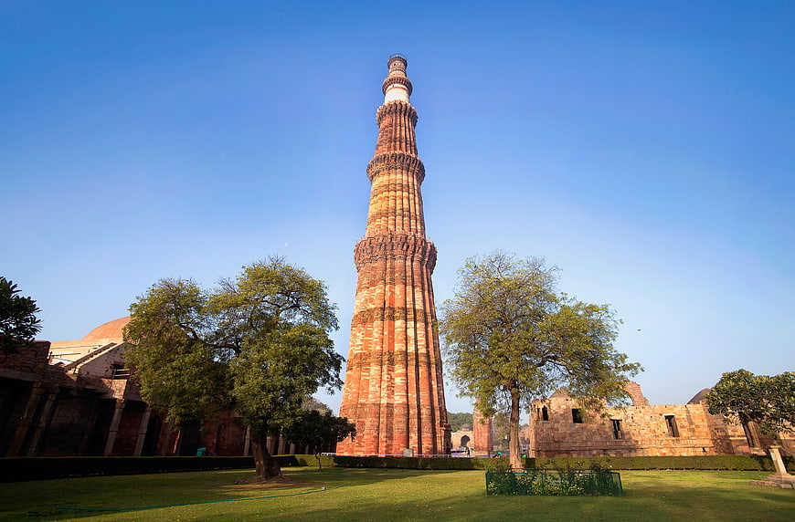 Qutub Minar Tower in Delhi India with Blue Sky and Green Grass