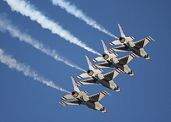 Four fighter jets flying in formation with smoke trails