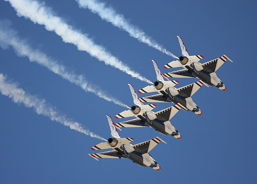 Four fighter jets flying in formation with smoke trails