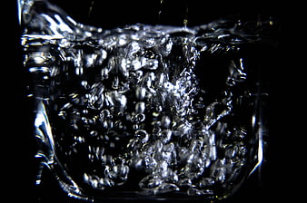 Close-up of splashing water in a glass against black background