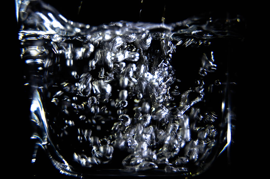 Close-up of splashing water in a glass against black background