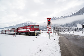 Red Train Crossing Snowy Mountain Road in Winter