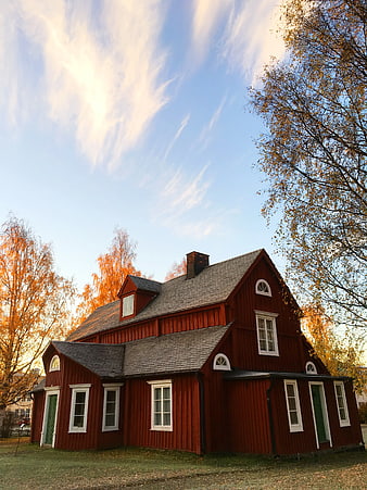 Traditional Red Wooden House in Autumn Landscape