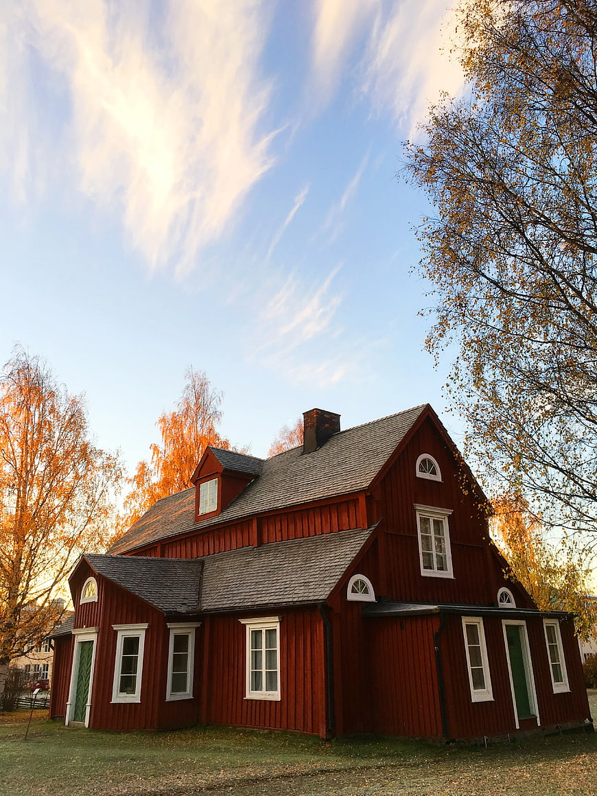 Traditional Red Wooden House in Autumn Landscape
