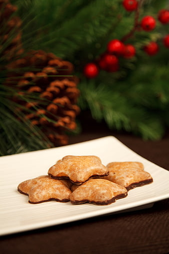Star-shaped gingerbread cookies on a white plate with Christmas decorations