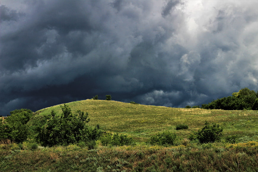 Dramatic storm clouds over rolling green hills