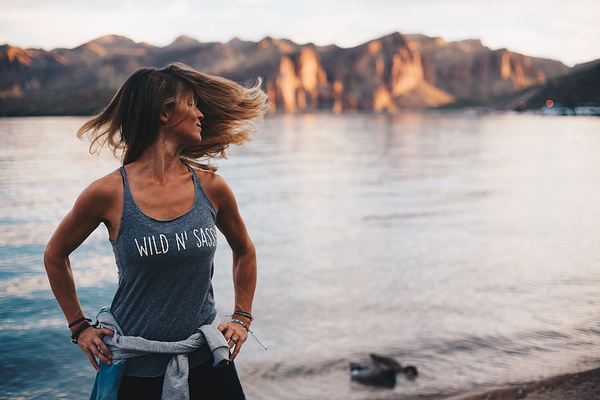 Woman in athletic wear standing by lake with mountains