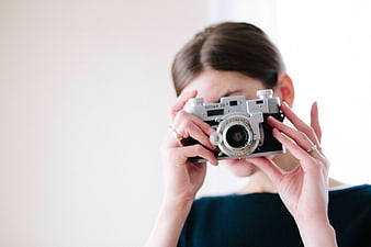 Woman holding vintage Kodak camera against white background