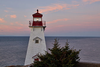 White Lighthouse with Red Roof at Sunset Over Ocean