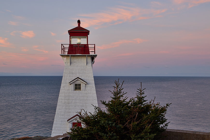 White Lighthouse with Red Roof at Sunset Over Ocean