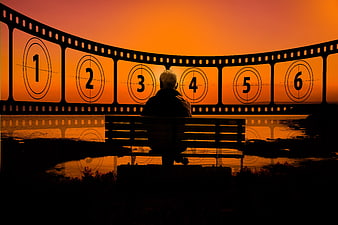 Silhouette of Person on Bench Before Curved Filmstrip at Sunset