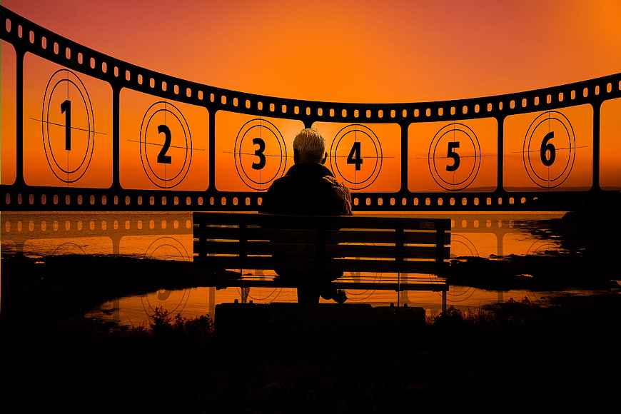 Silhouette of Person on Bench Before Curved Filmstrip at Sunset