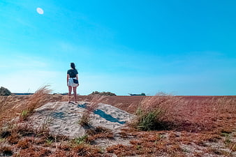 Woman Standing on Sand Dune Looking at Blue Sky