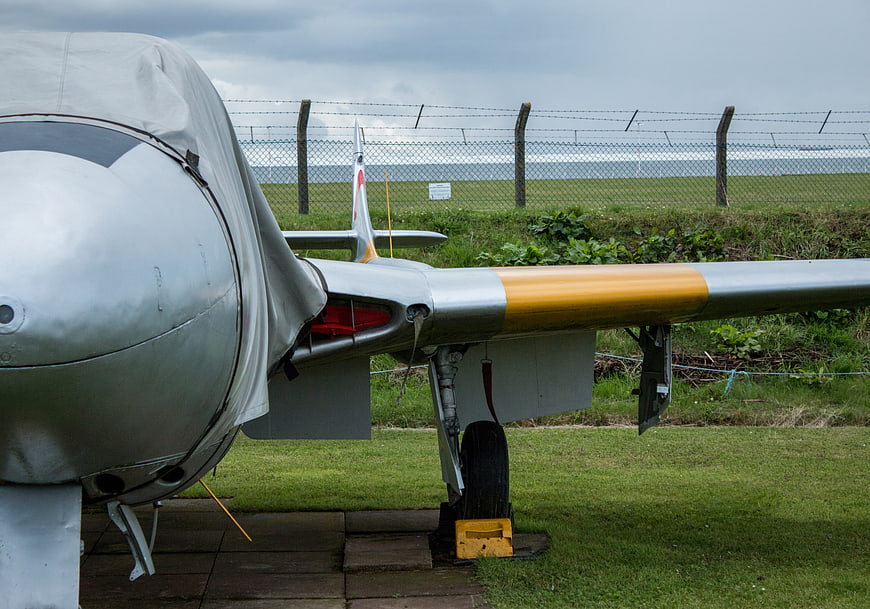 Close-up of vintage silver and yellow airplane wing on grass