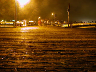 Low angle view of wet wooden pier at night with motion blur