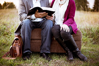 Couple reading book together on outdoor couch in nature