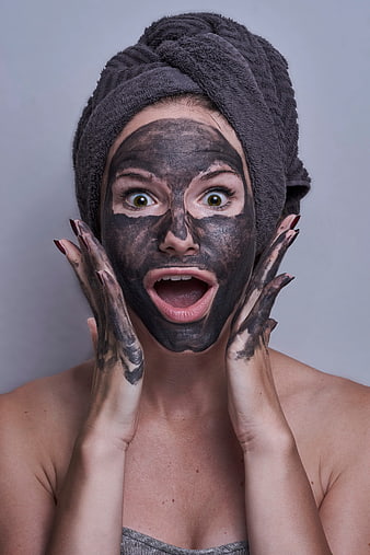 Woman with charcoal face mask and shocked expression