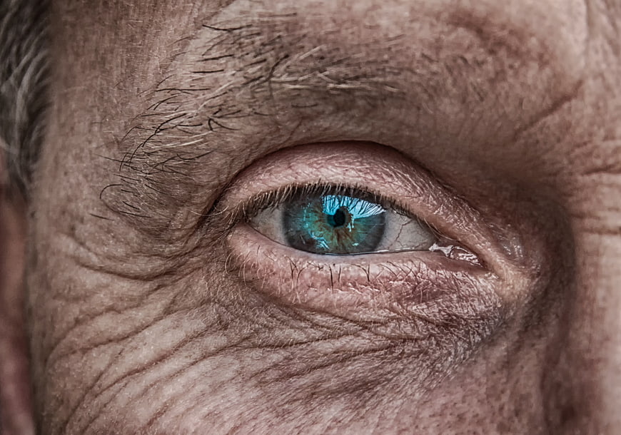 Close-up of elderly man's blue eye with wrinkled skin