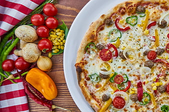 Fresh vegetable pizza with raw ingredients on wooden table