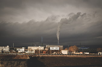 Industrial factory with smokestacks under dramatic cloudy sky
