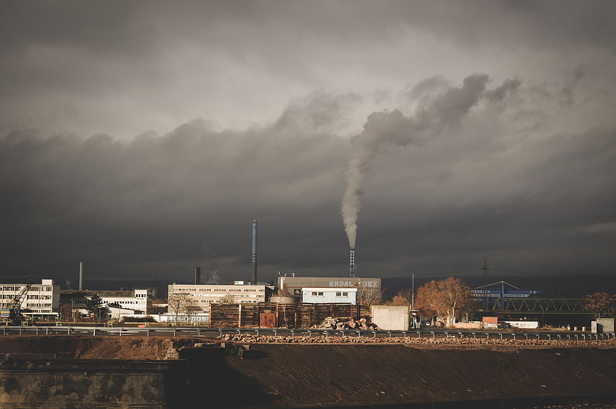 Industrial factory with smokestacks under dramatic cloudy sky