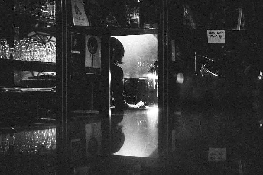 Silhouette of person sitting at dark bar counter