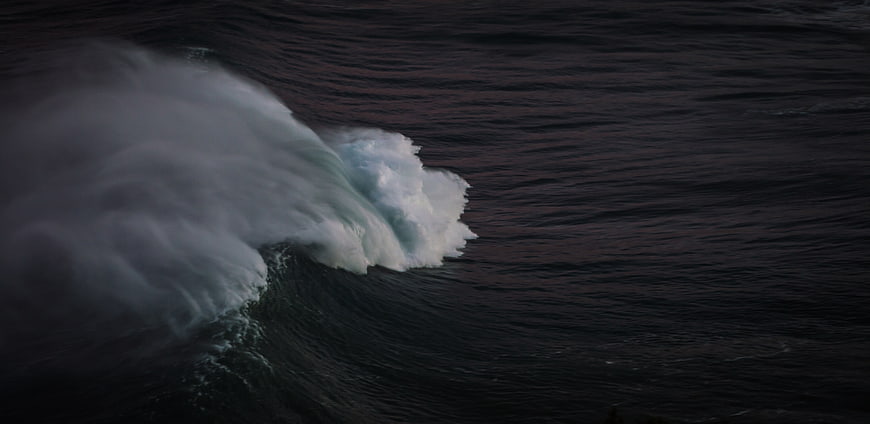 Dramatic dark ocean wave crashing with white foam
