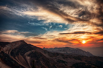 Dramatic sunset over rugged mountain peaks with golden clouds
