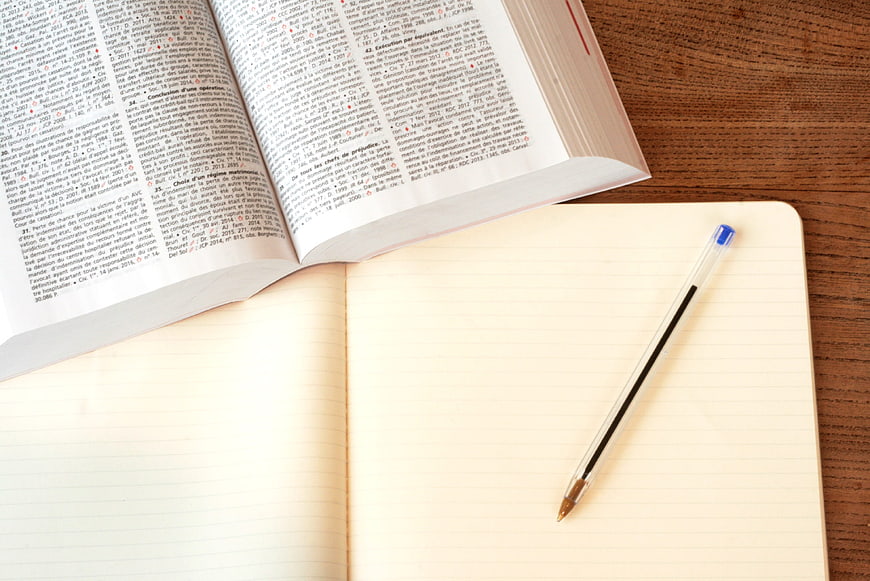 Open law book and notebook with pen on wooden desk