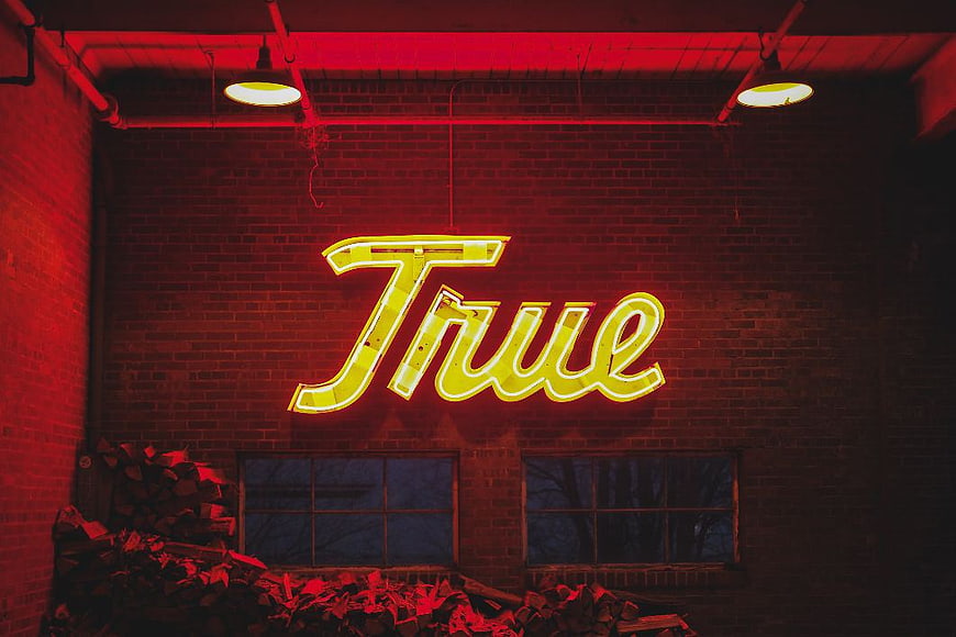 Yellow True Neon Sign on Red Brick Wall
