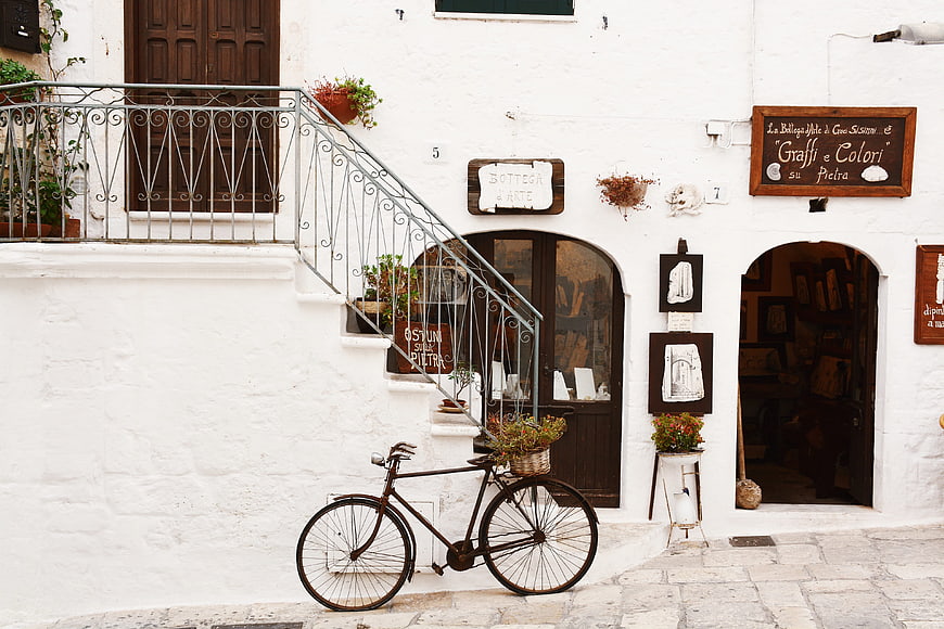 Vintage bicycle parked in front of white Italian shop facade