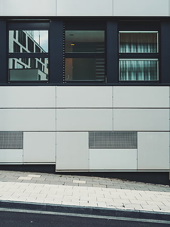 Modern minimalist building facade with geometric windows and white panels