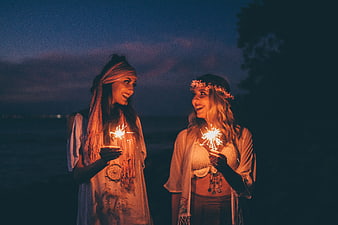 Two Women Holding Sparklers at Night Beach