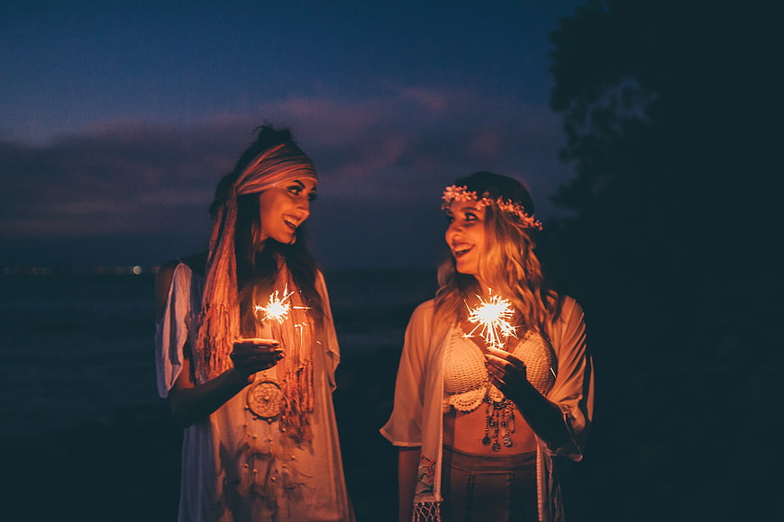 Two Women Holding Sparklers at Night Beach