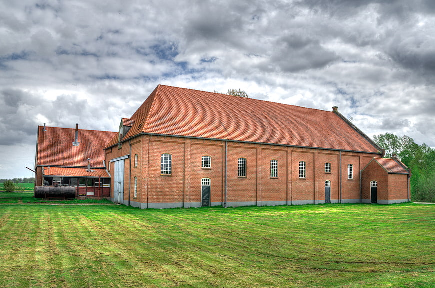 Old red brick factory building with green lawn and cloudy sky