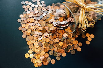 Spilled Pennies from Glass Jar on Dark Background