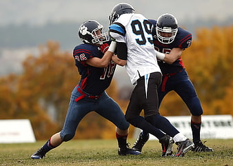 American Football Players Tackling on Grass Field