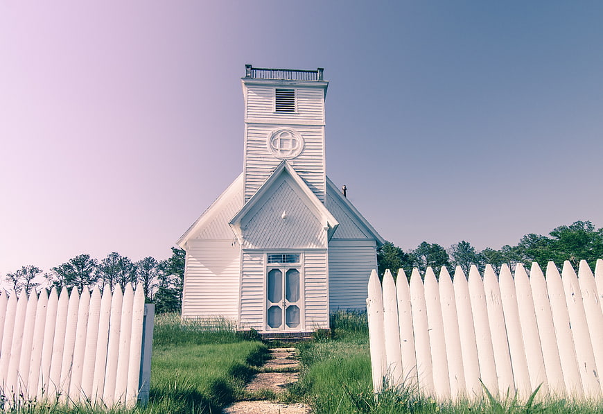 White wooden chapel with picket fence and blue sky