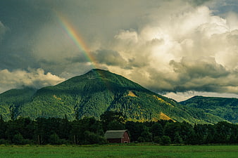 Red Barn in Green Field with Rainbow Over Mountain